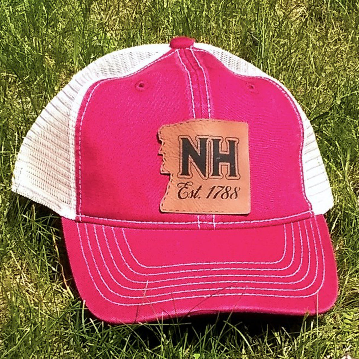 Red trucker hat with a leather patch on grass