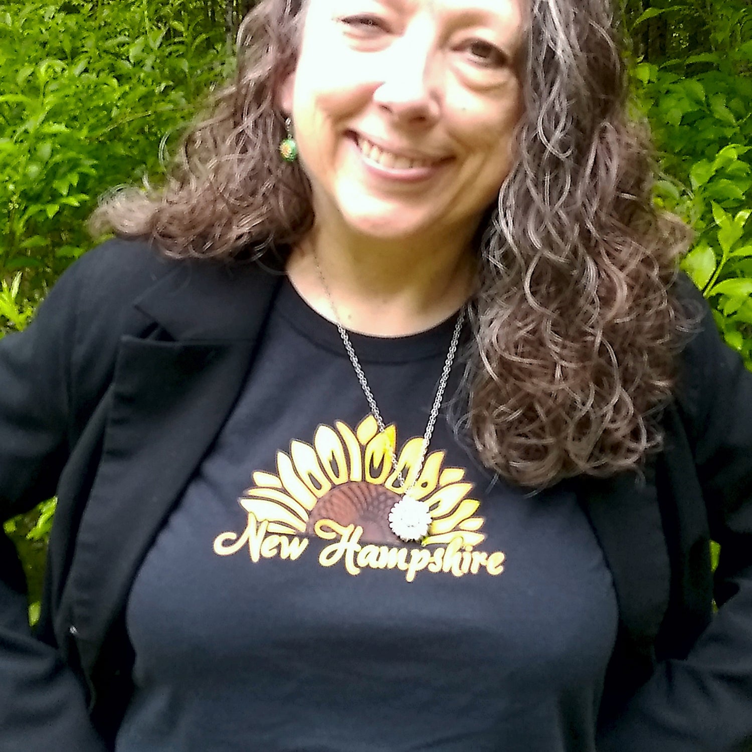Person wearing a black shirt with 'New Hampshire' and a sunflower design outdoors.