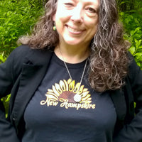 Person wearing a black shirt with 'New Hampshire' and a sunflower design outdoors.