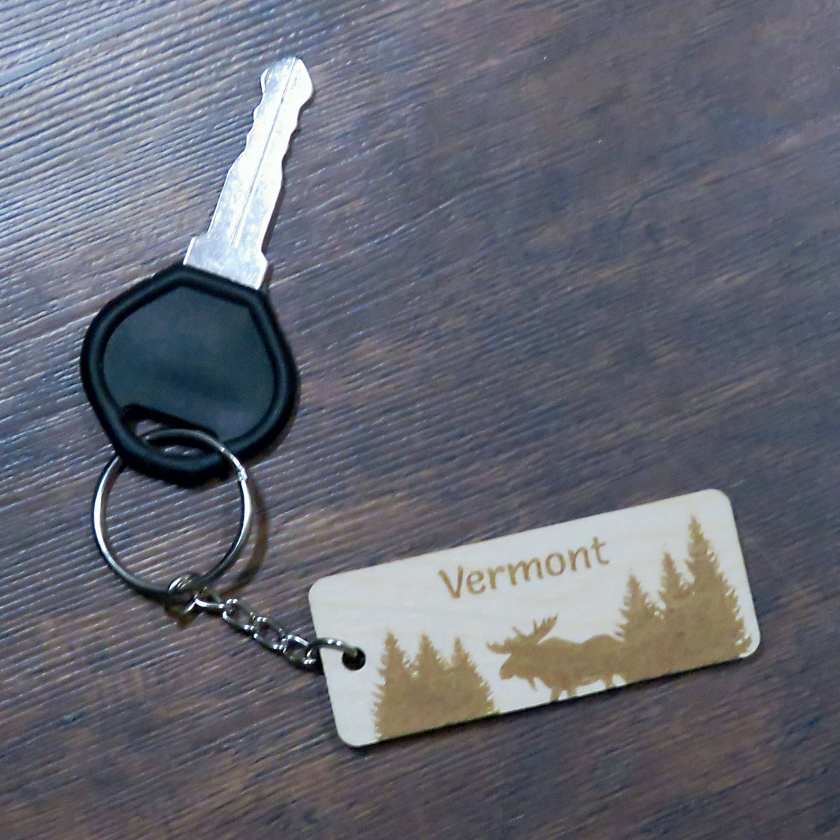 Keychain with 'Vermont' and moose design on a wooden surface