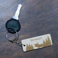 Keychain with 'Vermont' and moose design on a wooden surface