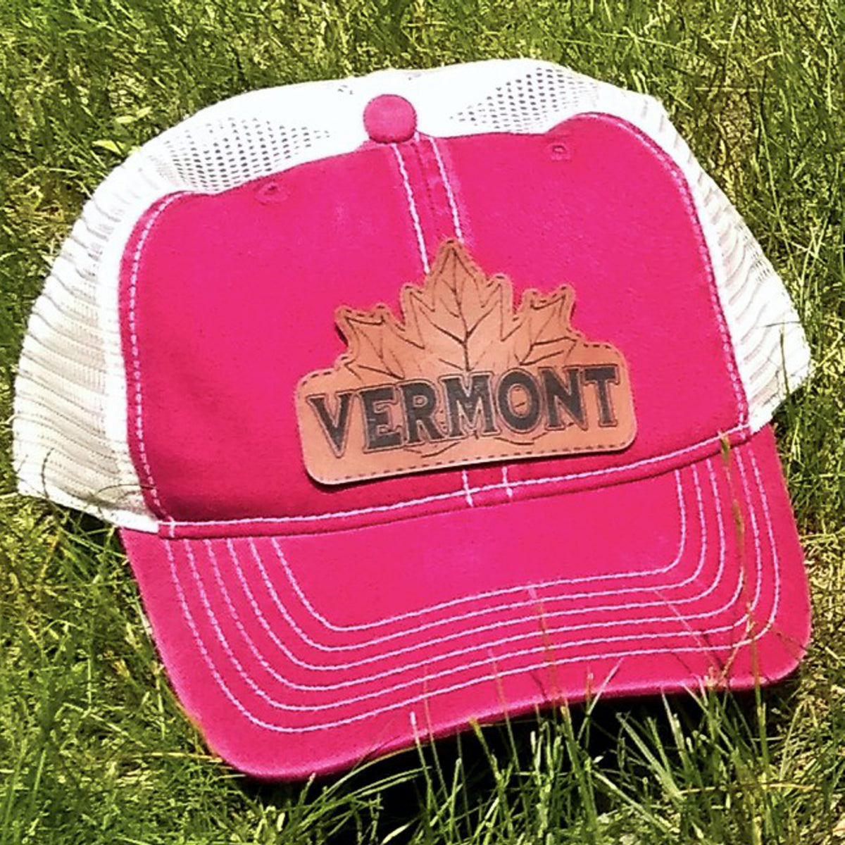 Red cap with 'Vermont' and a maple leaf on a grass background