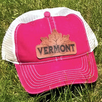 Red cap with 'Vermont' and a maple leaf on a grass background