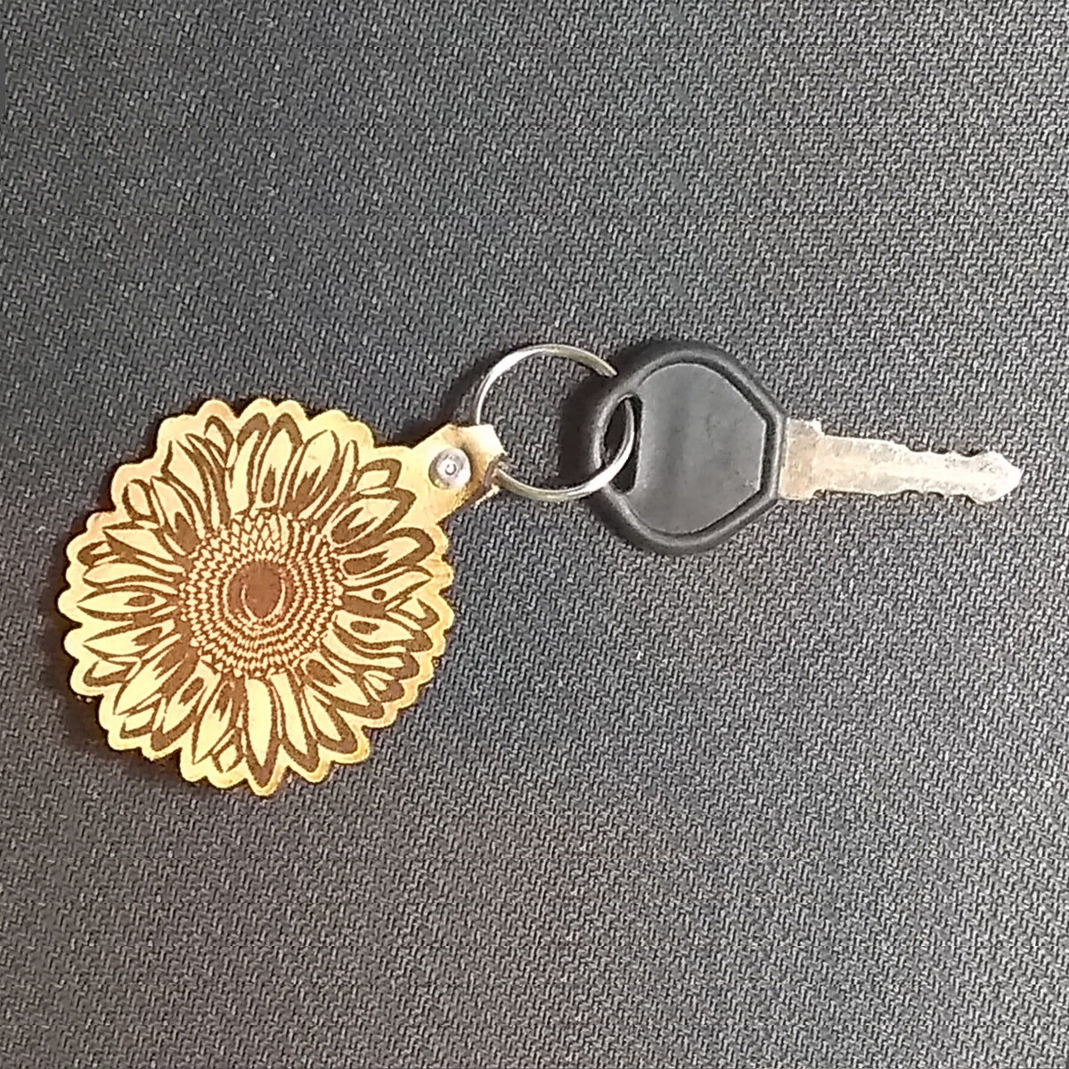 Keychain with sunflower design on a gray surface