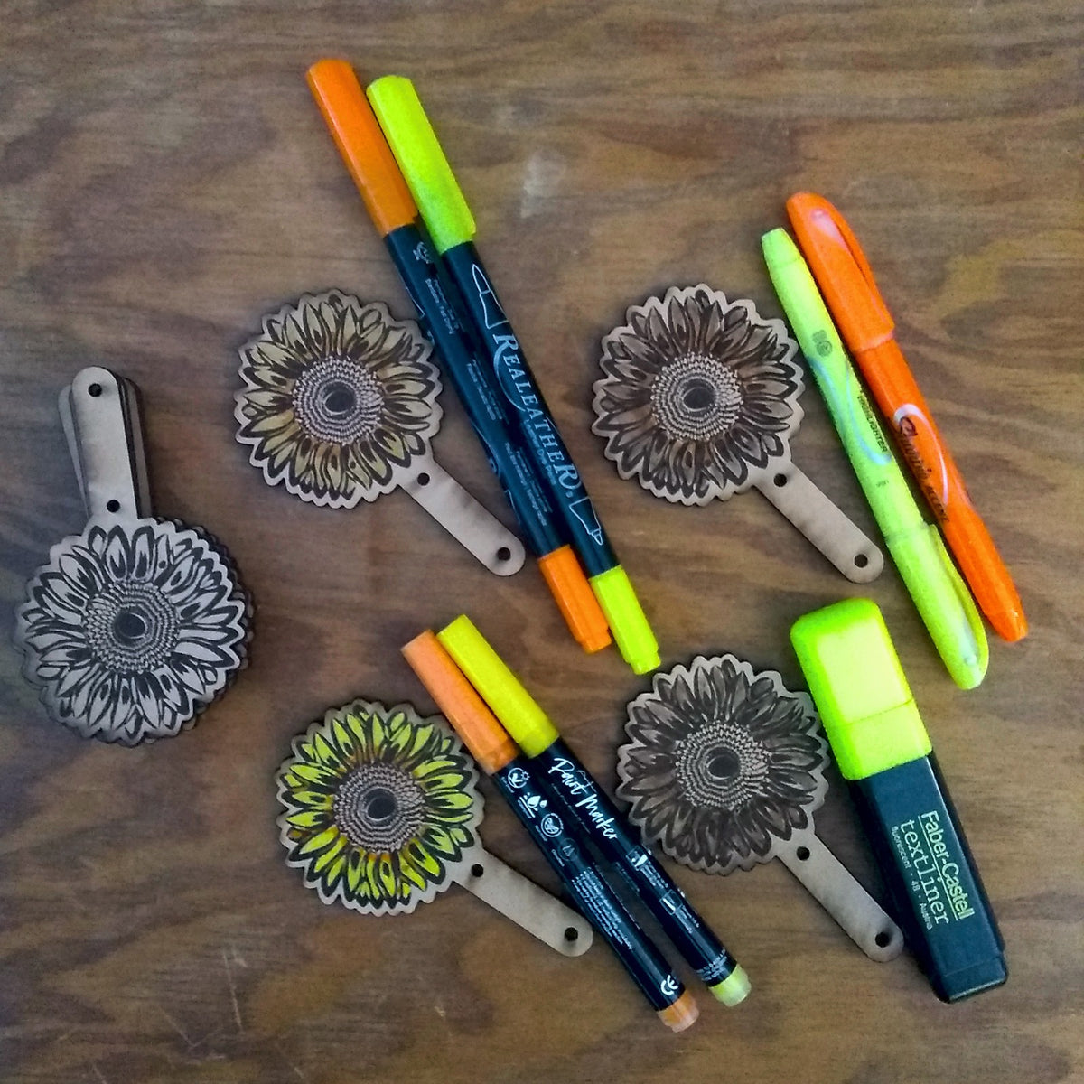 Colorful markers and floral designs on a wooden surface