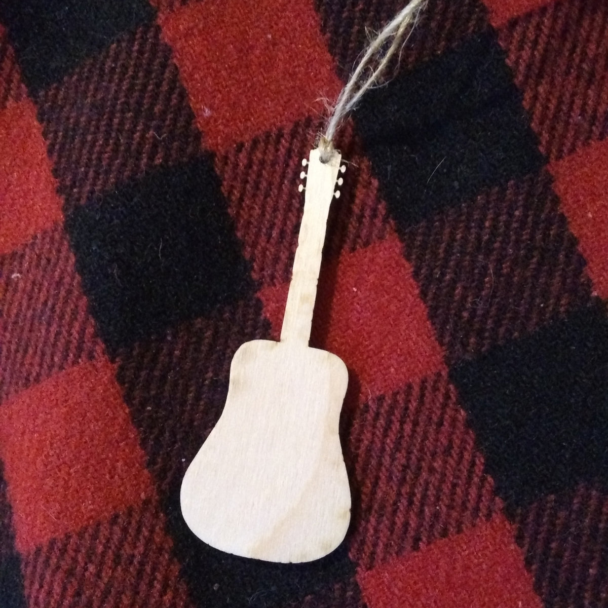 Wooden guitar-shaped ornament on a red and black checkered fabric background