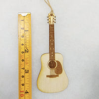 Small wooden guitar ornament next to a ruler on a light gray background