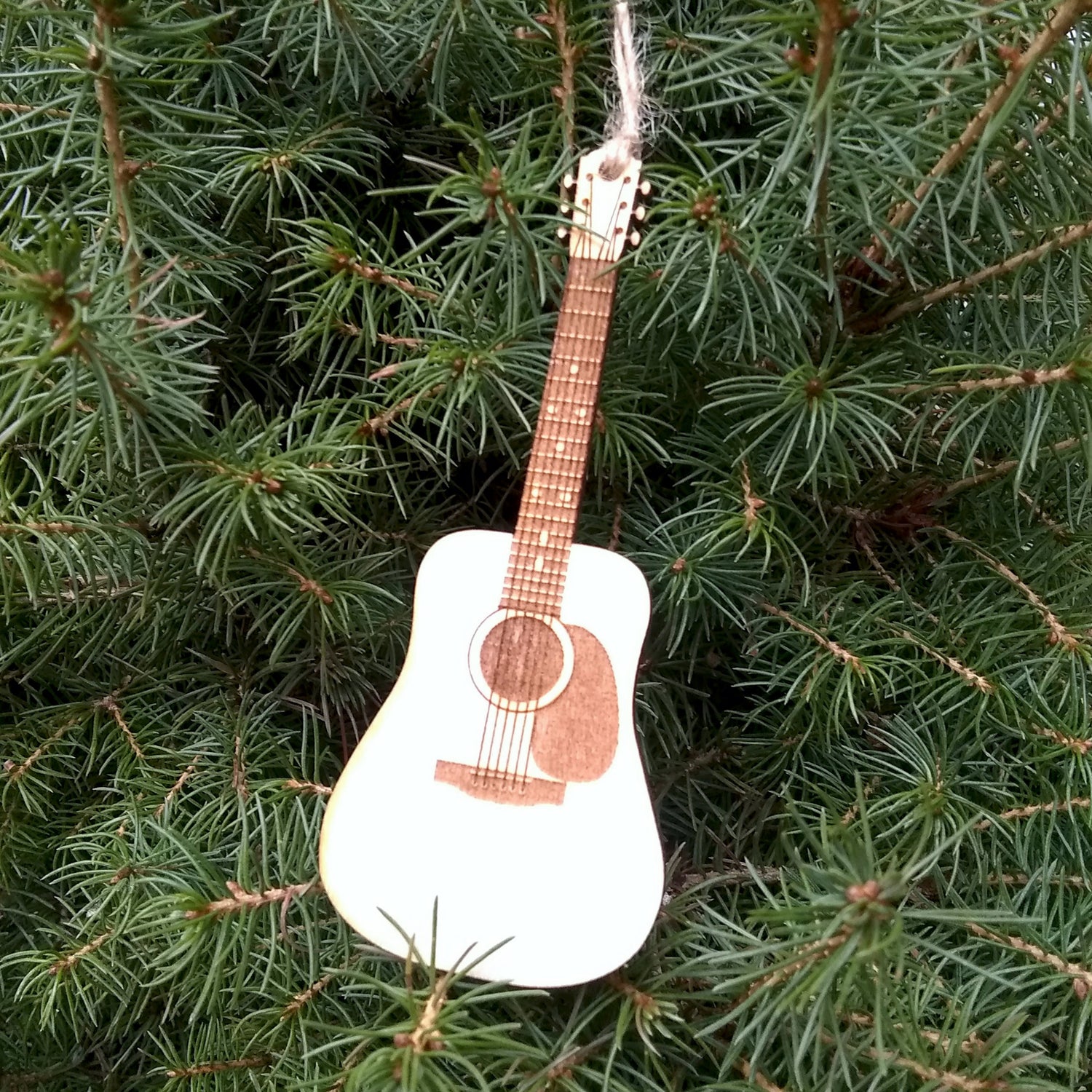 Decorative guitar ornament hanging on a pine tree