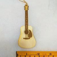 Small wooden guitar ornament on a white background with a ruler for scale.