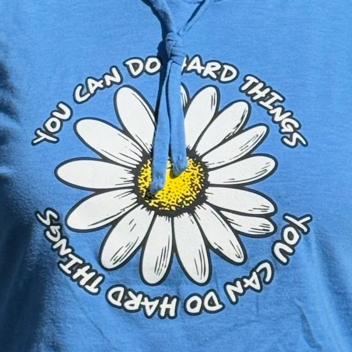 Blue hooded t-shirt with a white daisy and motivational text on a blue background