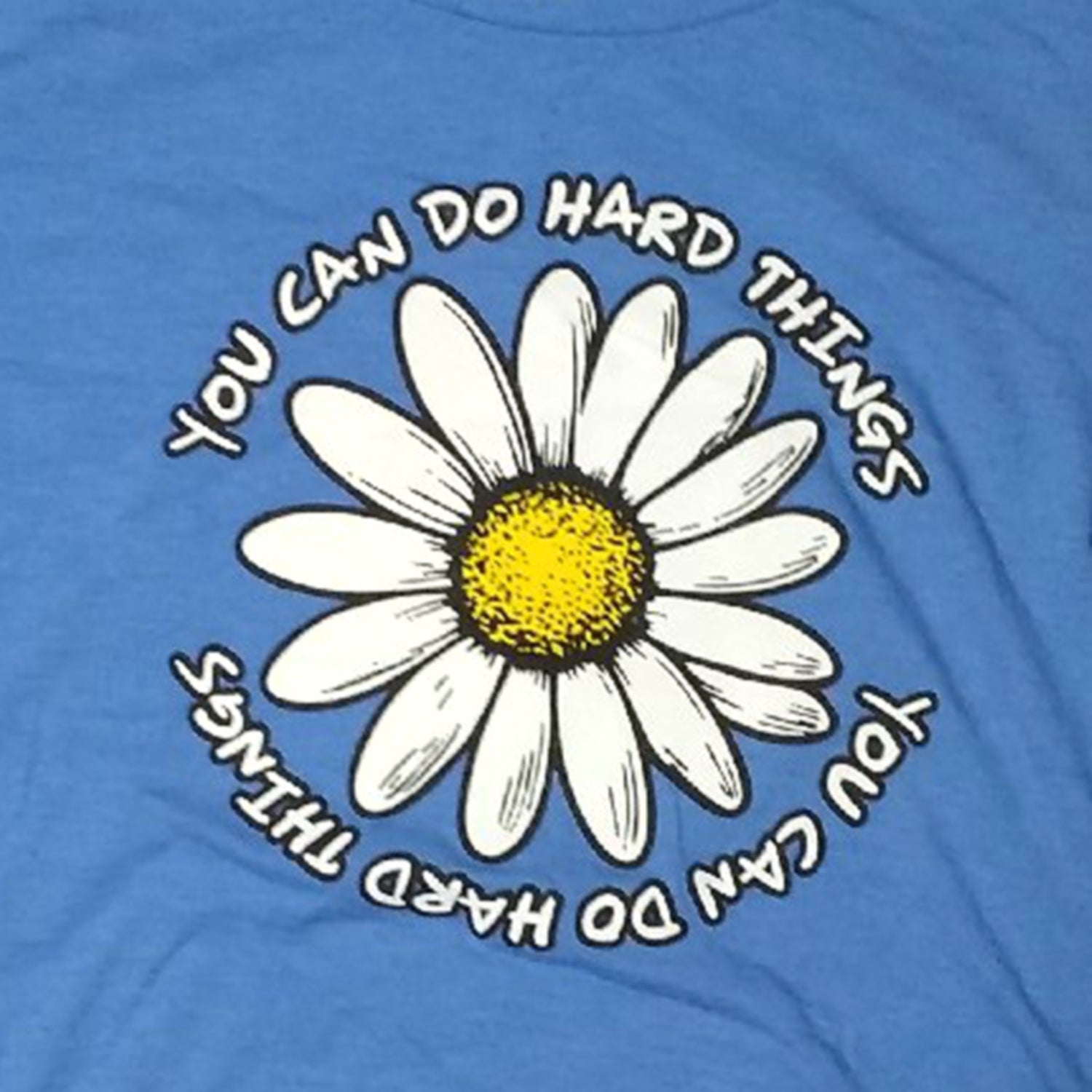 Blue t-shirt with a white daisy and motivational text on a blue background