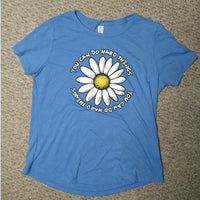 Blue t-shirt with a daisy graphic and text on a beige carpet