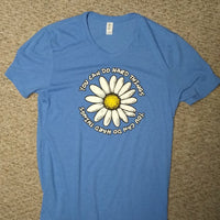 Blue t-shirt with a daisy graphic and text on a beige carpet background