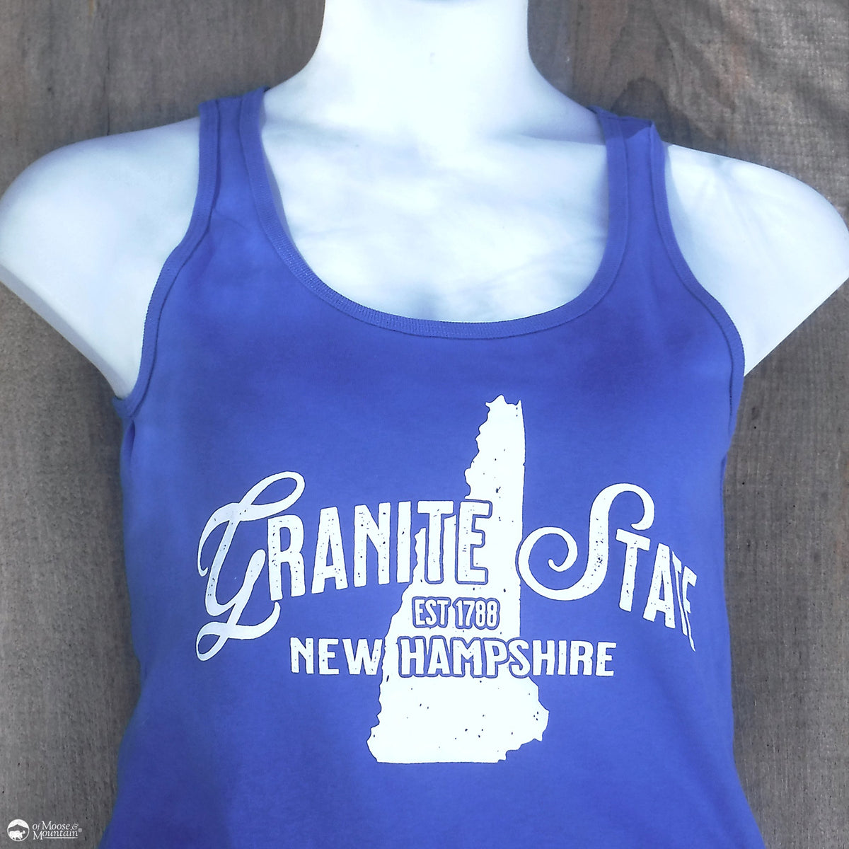Blue tank top with 'Granite State New Hampshire' text on a mannequin against a wooden background