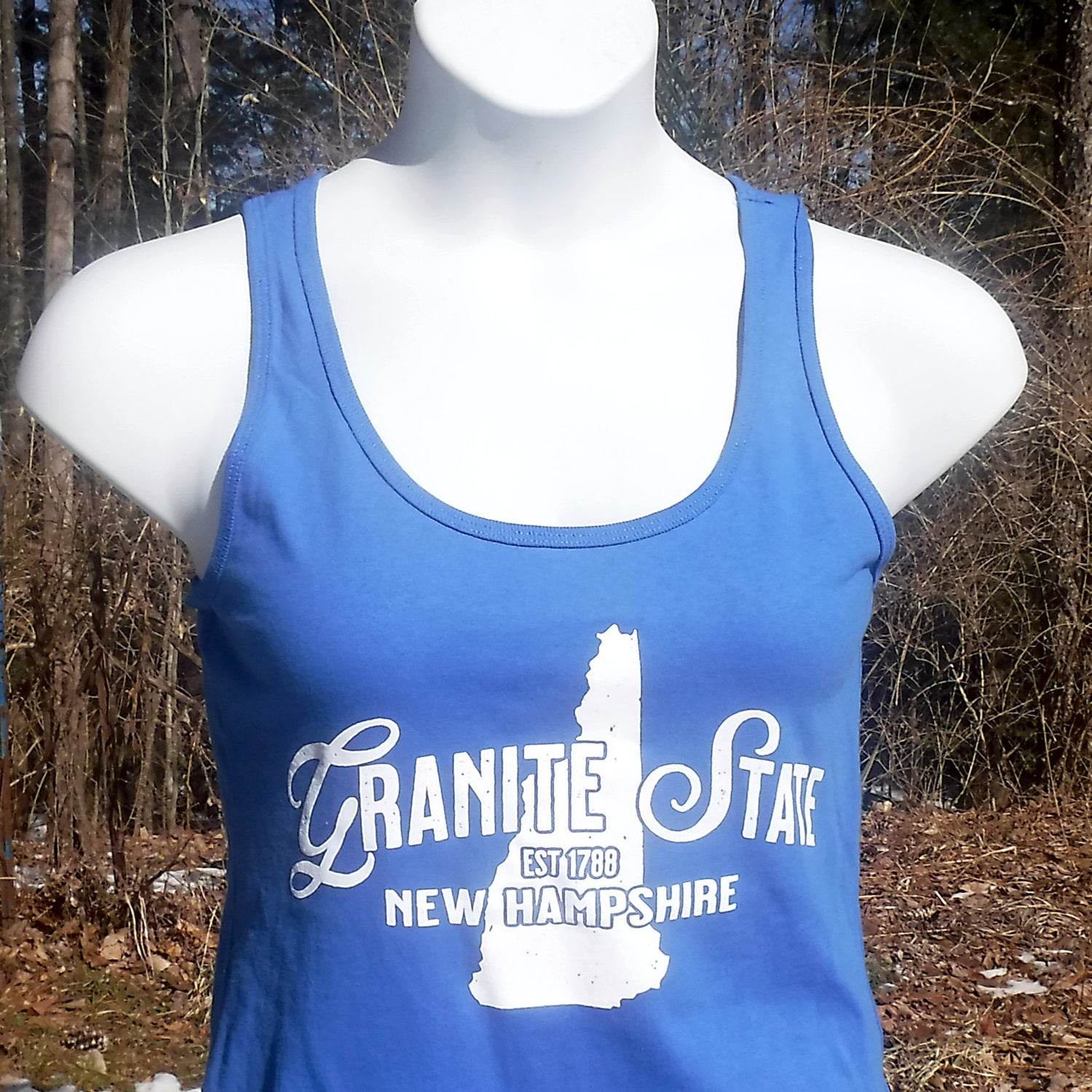 Blue tank top with 'Granite State New Hampshire' text on a mannequin against a natural background.