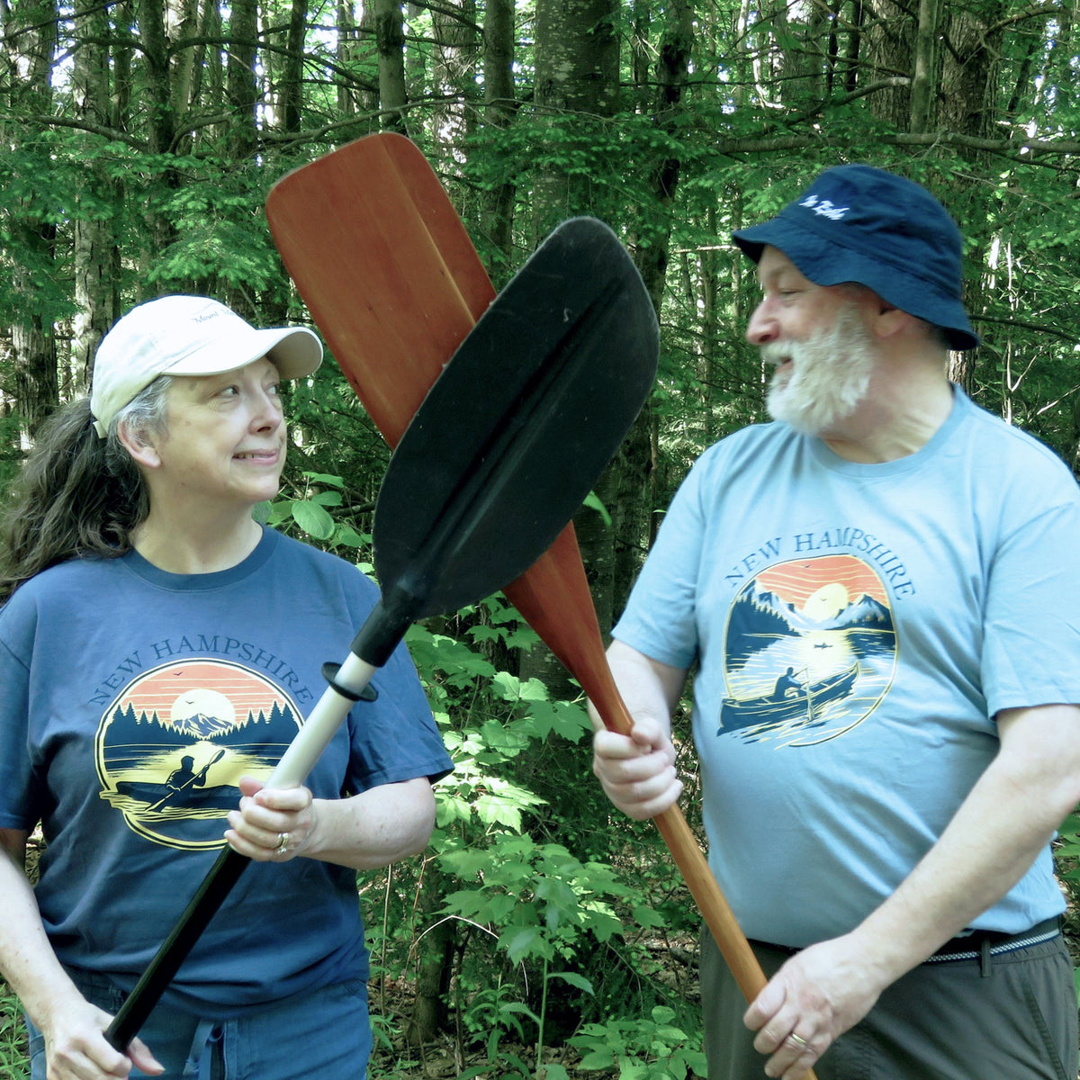 Two people holding paddles in a forest setting